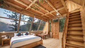A wooden cabin bedroom with a bed, a desk, and a staircase.