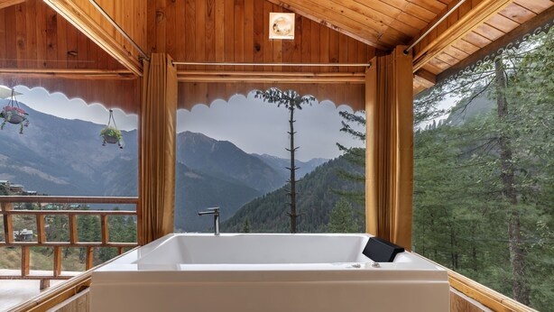 A wooden cabin with a large bathtub and a scenic mountain view.