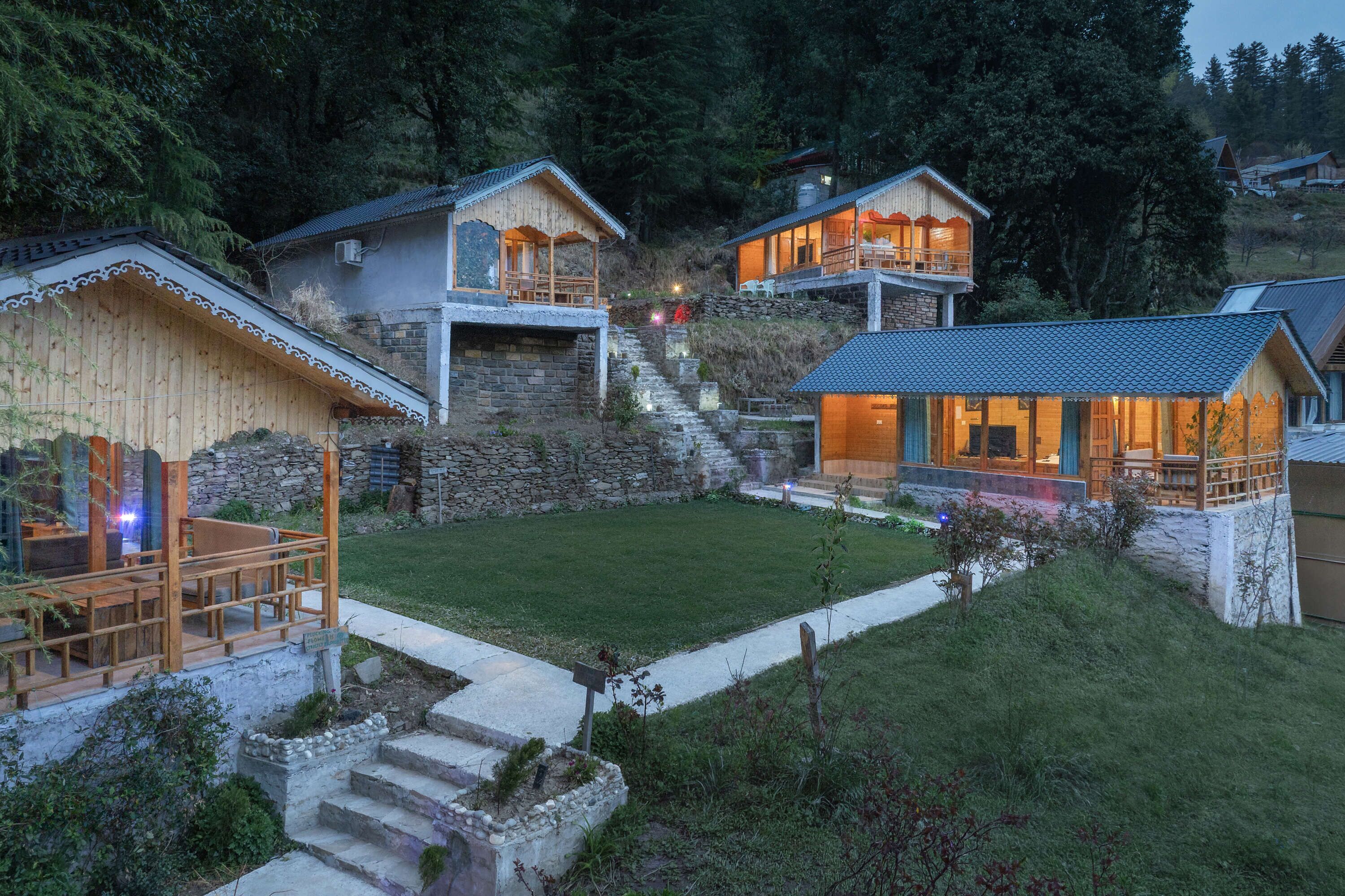 A hillside property with multiple wooden cabins, a stone staircase, and a well-maintained lawn.
