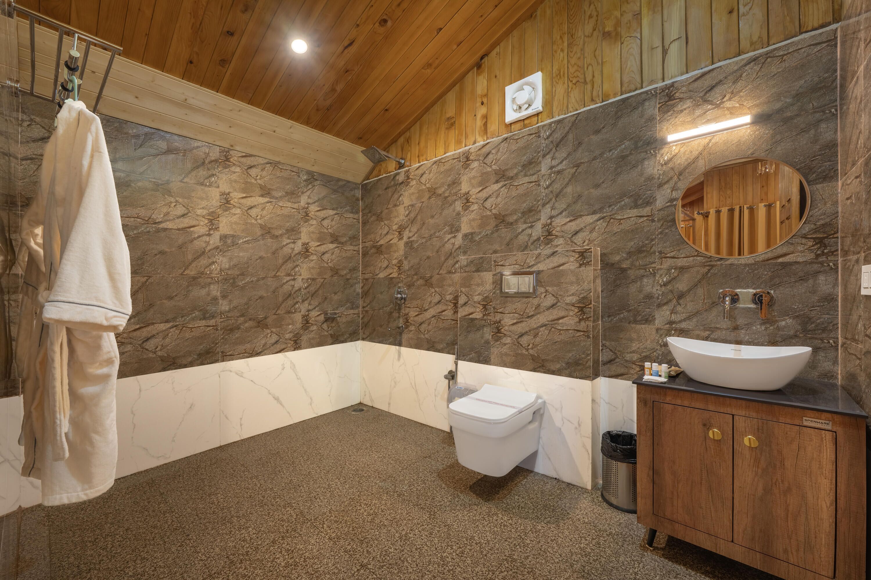 Une salle de bain avec un mur en marbre, des toilettes, un lavabo et un meuble-lavabo en bois.