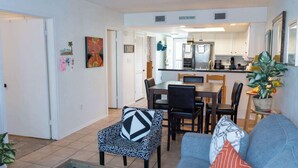 A modern living room with a dining area, kitchen, and a hallway leading to bedrooms. - Cozy Family Retreat - Steps to Beach - Pool - Hot Tub (South Padre Island)