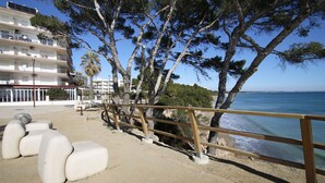 A coastal promenade with a wooden railing, a sandy path, and a row of white benches. - Panoramic B6 by Parc Mont-roig Apartment (Miami Playa)