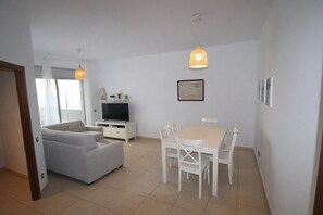 A modern living room with a sofa, TV, dining table, and chairs. - Panoramic B6 by Parc Mont-roig Apartment (Miami Playa)