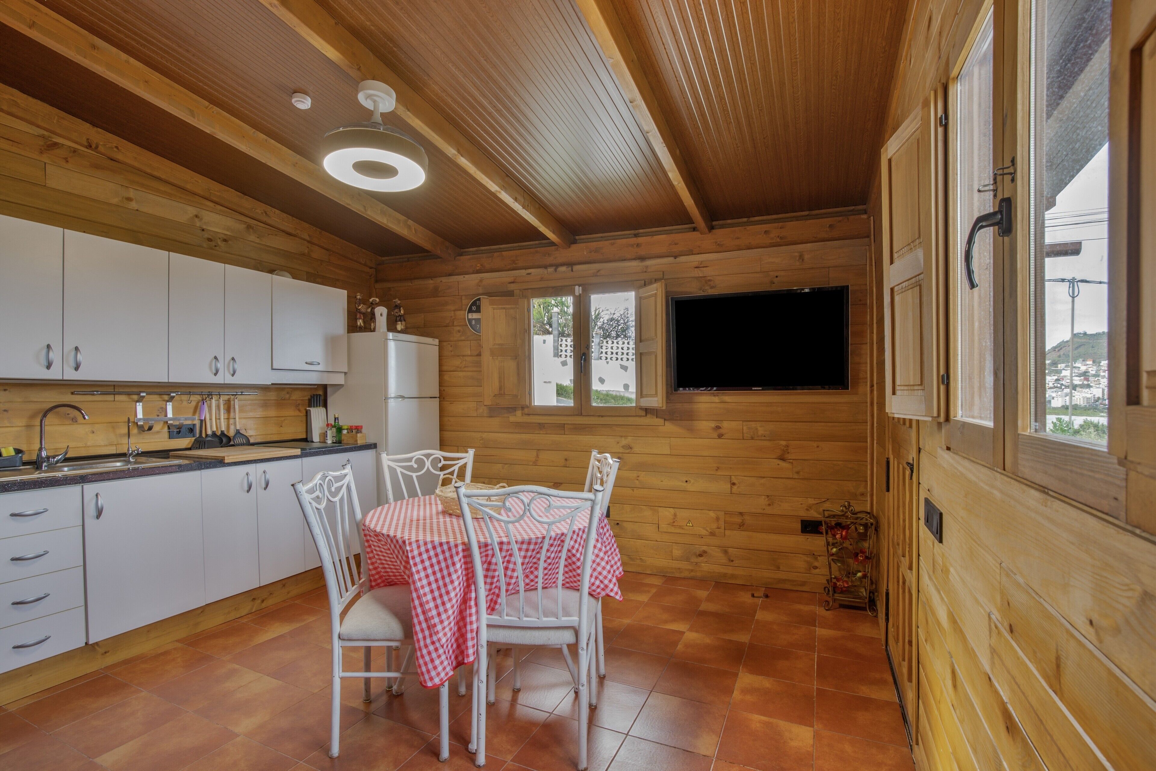 L’intérieur d’un chalet en bois comprend une cuisine, un coin repas et une grande fenêtre.
