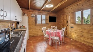 Ein Holzinterieur mit einer Küche, einem Esstisch, Stühlen und einem Fenster mit Blick.