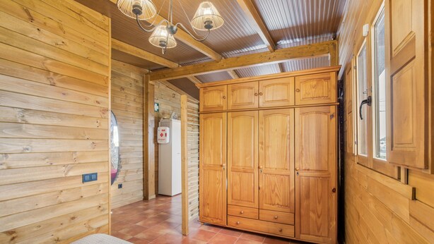 Ein Holzinnenraum mit Bett, Kleiderschrank und Deckenventilator.