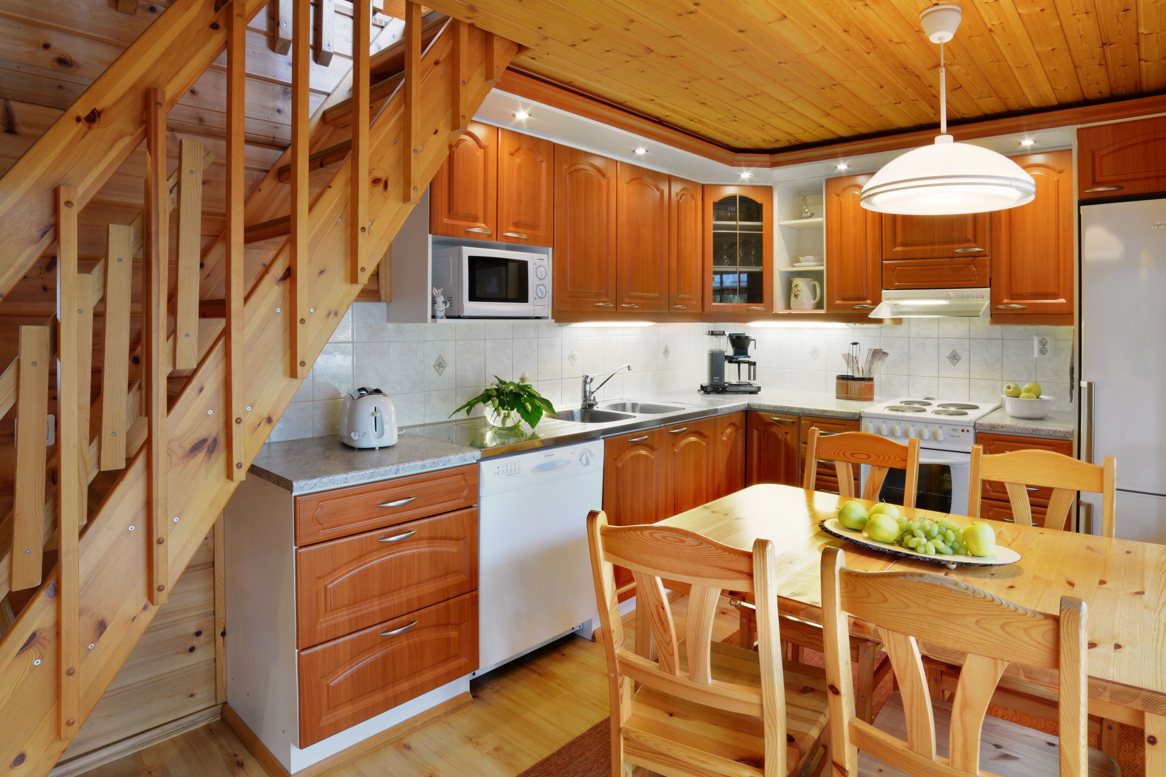 A kitchen with wooden cabinets, a microwave, a dishwasher, a stove, and a dining table with chairs.