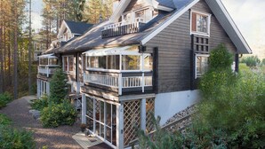 Een tweelaags huis met balkon, terras en uitzicht op het omliggende bos.