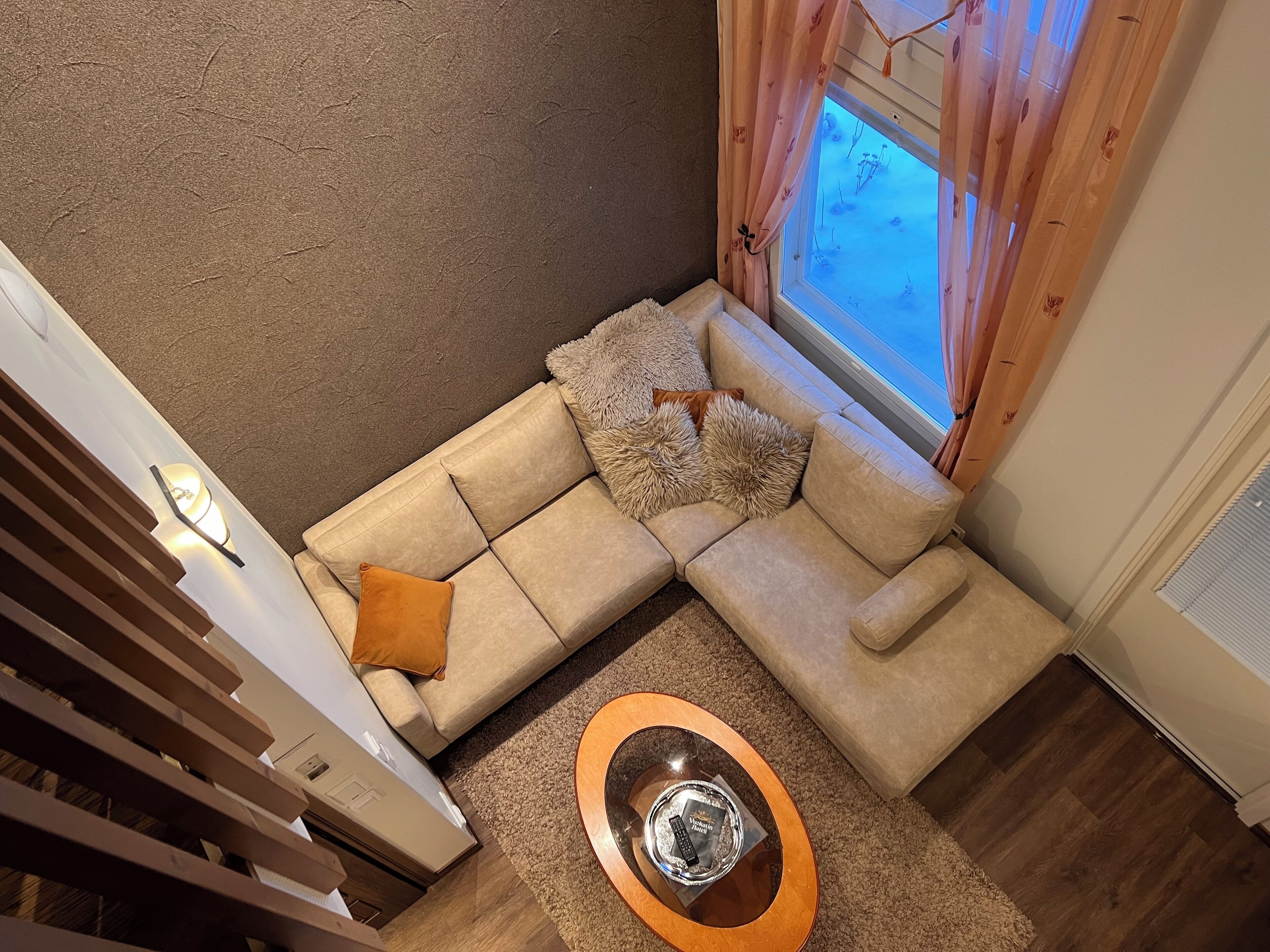 A modern living room with a sectional sofa, a coffee table, and a window with curtains.