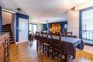 A dining area with a table and chairs, a staircase, and a view of the outside. - The 8th Heaven Above Dijon – Duplex with Panoramic (Dijon)