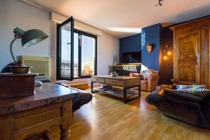 A living room with a wooden coffee table, a sofa, a TV, and a cabinet. - The 8th Heaven Above Dijon – Duplex with Panoramic (Dijon)