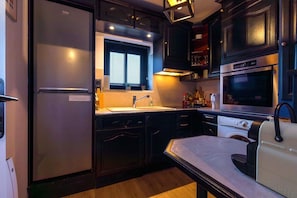A compact kitchen with a refrigerator, sink, microwave, oven, and a small dining table. - The 8th Heaven Above Dijon – Duplex with Panoramic (Dijon)