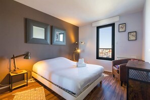 A bedroom with a bed, bedside lamps, a desk, a chair, and a window with a view. - The 8th Heaven Above Dijon – Duplex with Panoramic (Dijon)
