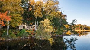 Ein Seeufergrundstück mit einer Hütte, umgeben von Herbstlaub und einem stillen See.