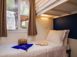 Ein Etagenbett mit Fenster, ein Kopfkissen mit Logo, ein Buch und ein blaues Handtuch.