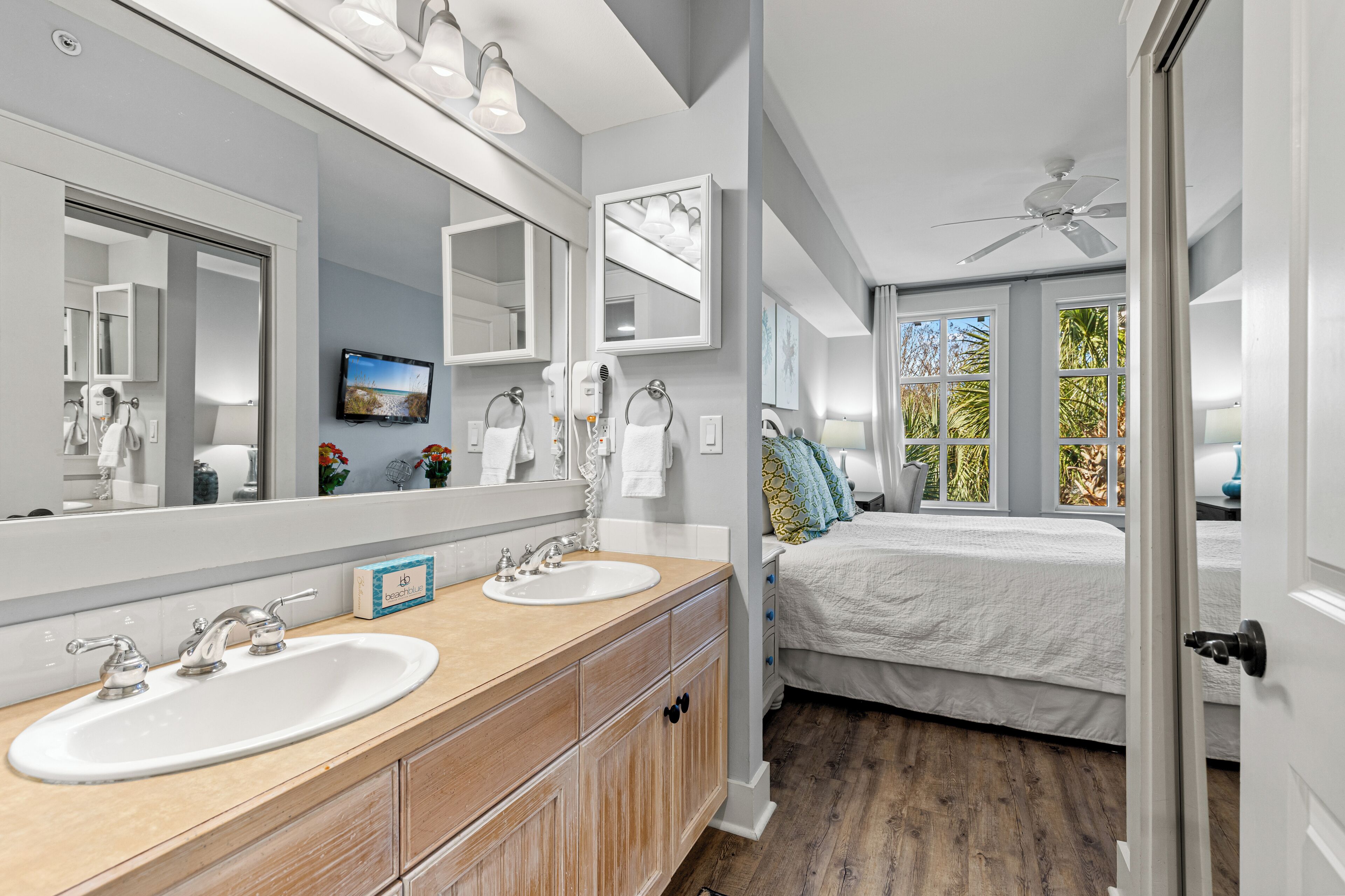 A modern bathroom with two sinks, a large mirror, and a ceiling fan.