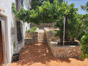 A stone staircase leading up to a building with a white exterior and a vine-covered pergola.