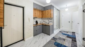 A hallway with a kitchen area featuring grey cabinets, a wooden countertop, and a marble backsplash.