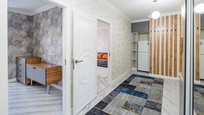 A modern room with a marble wall, a wooden desk, a white door, a patterned rug, and a white wardrobe.