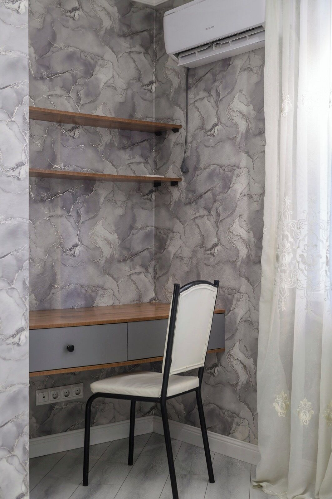 A study area with a desk, chair, and marble-patterned walls.