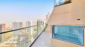 Een modern appartement met balkon en uitzicht over een stadsgezicht, een zwembadje en een zicht op omliggende gebouwen.