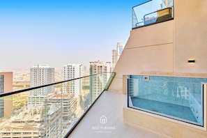 Eine moderne Wohnung mit Balkon und Blick auf eine Stadtlandschaft, einem kleinen Pool und umliegende Gebäude.