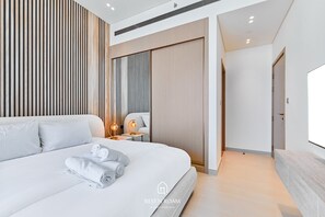 Ein modernes Hotelzimmer mit einem großen Bett, einem Nachttisch mit einer Lampe und einem Kleiderschrank.