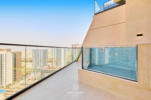 Eine moderne Wohnung mit Balkon und Blick auf die Stadt, darunter ein großes Fenster mit Ausblick auf Gebäude und einen Pool.