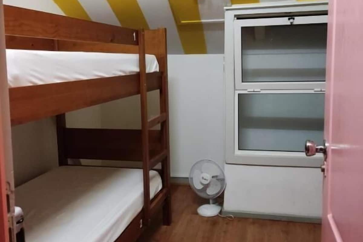 Dormitorio con literas, un ventilador y una ventana.