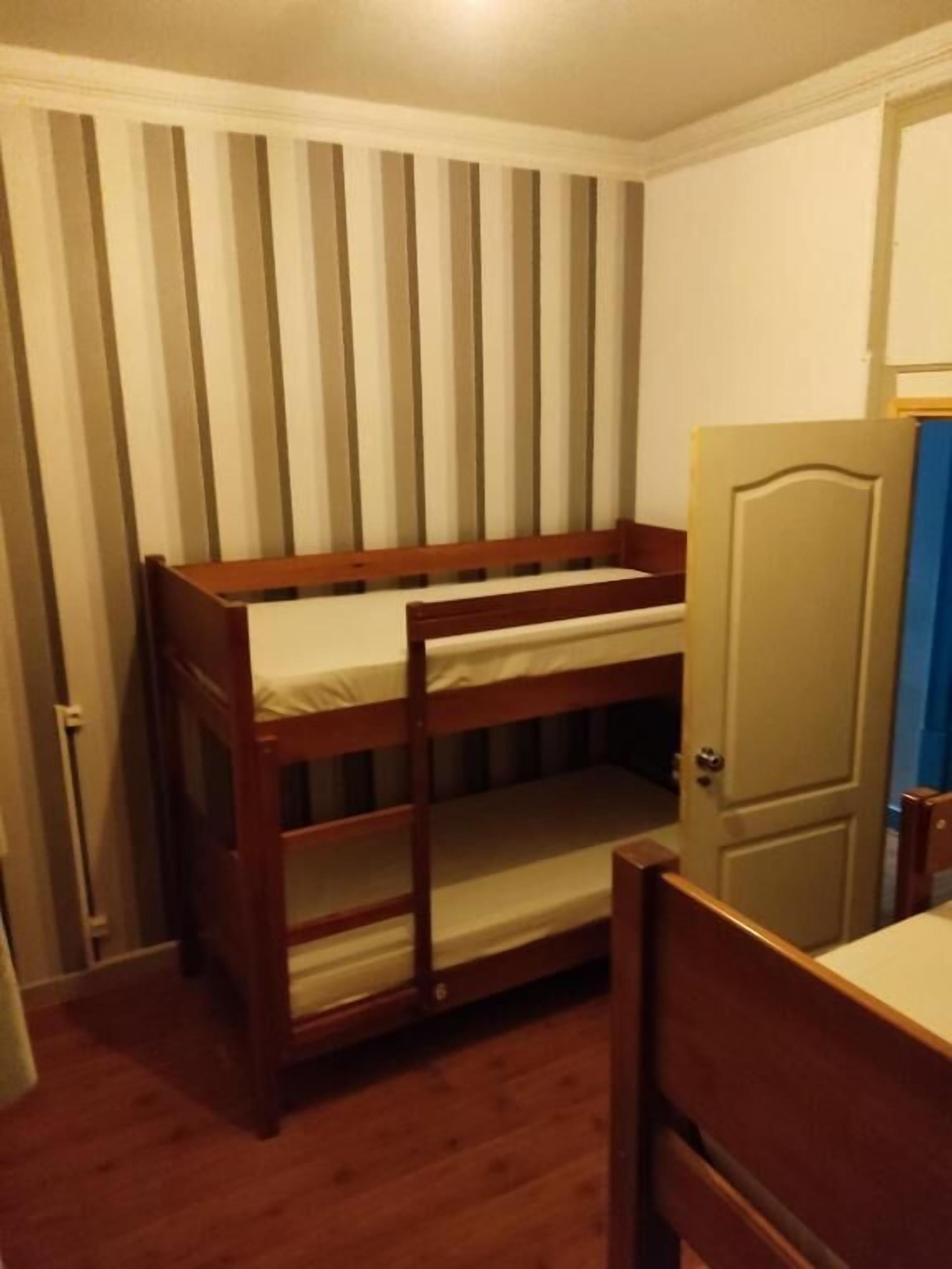 A room with a bunk bed, a door, and a chair.