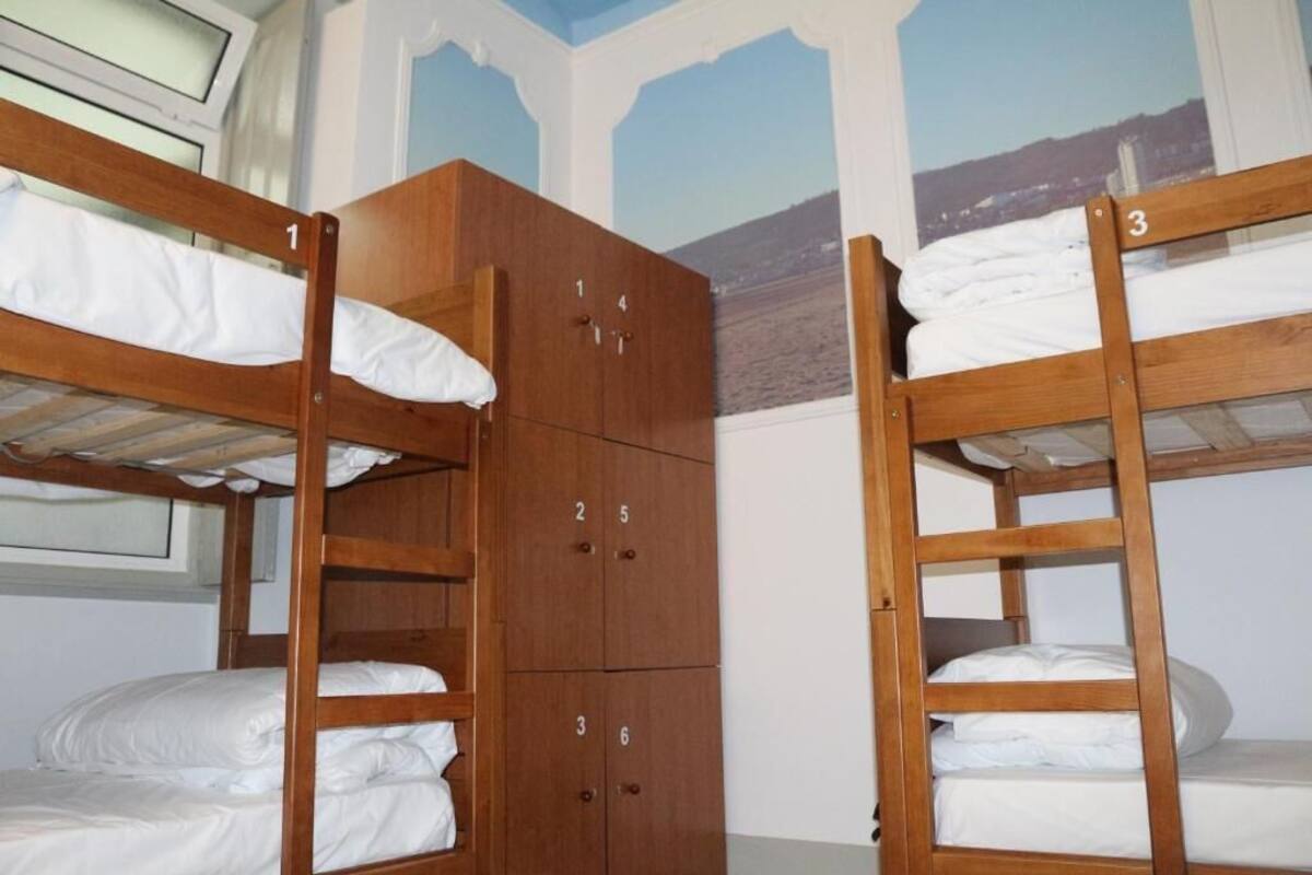 Dormitorio con literas, un armario de madera y una ventana.