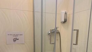 A bathroom with a toilet, a glass shower enclosure, and a hand dryer. - Meeting Hostel (Figueira da Foz)
