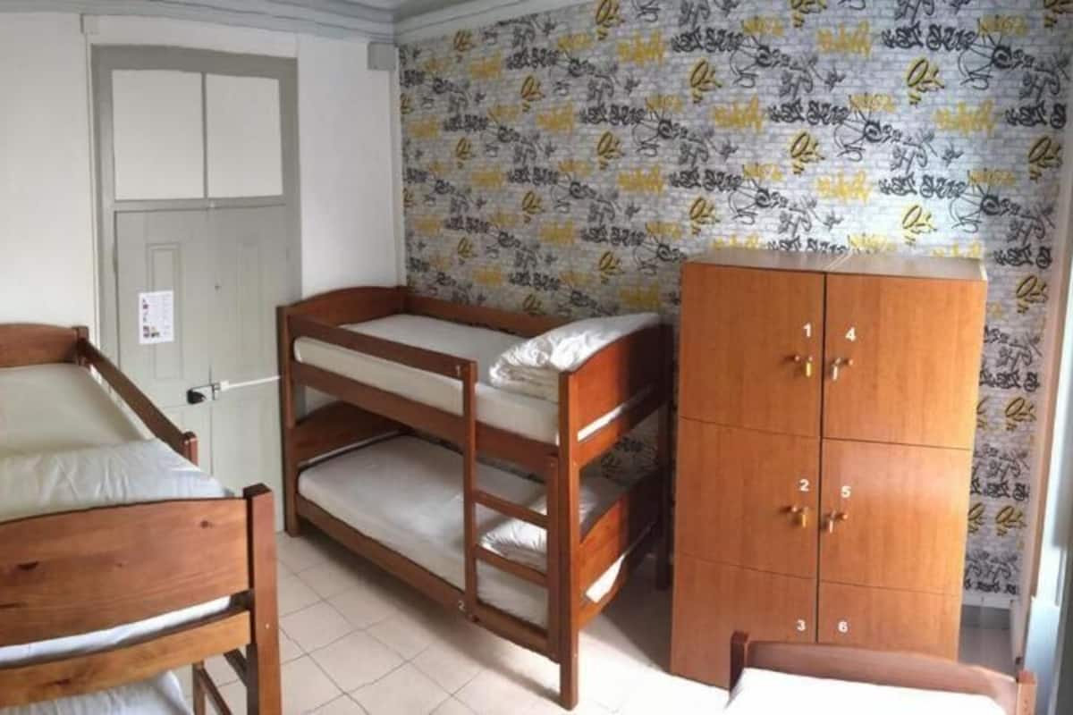 Una habitación con una cama litera, un armario de madera y una puerta.