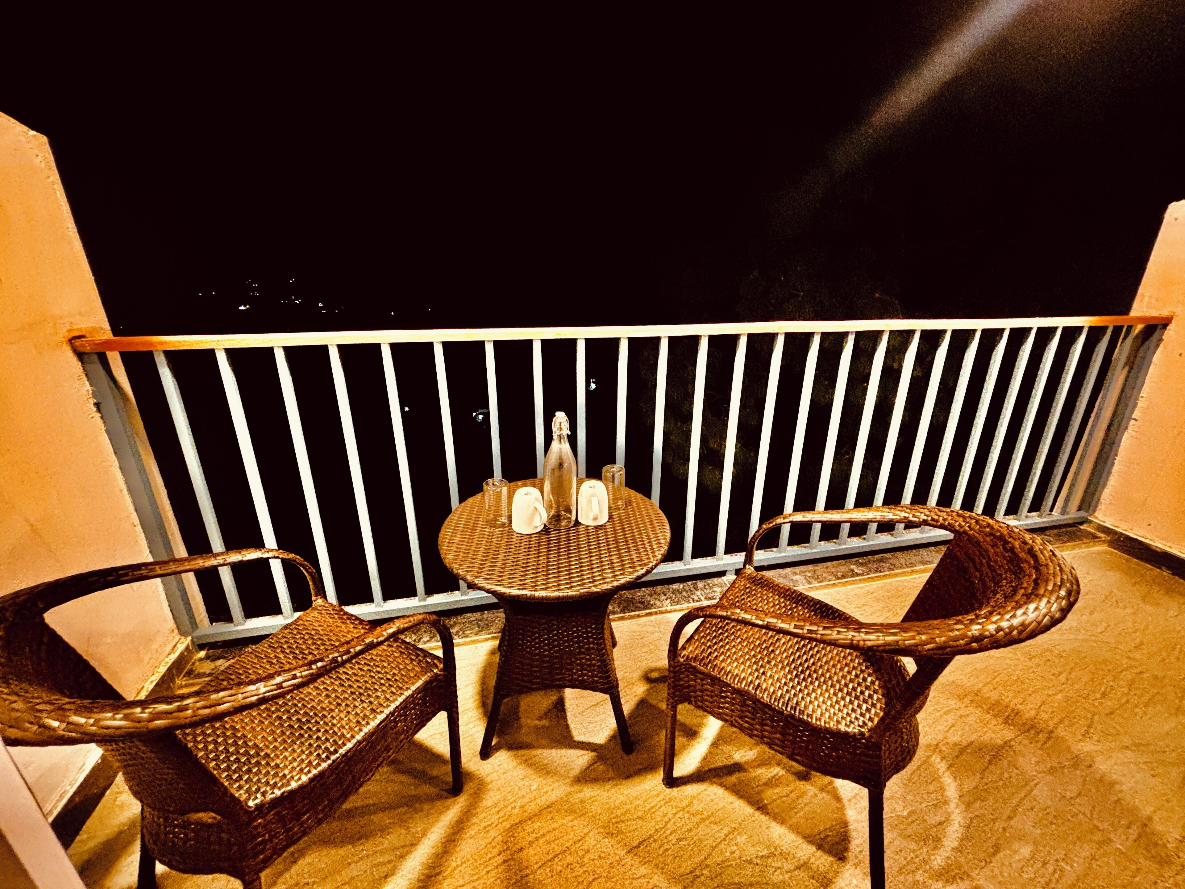 A balcony with wicker furniture, a small table, and a bottle.