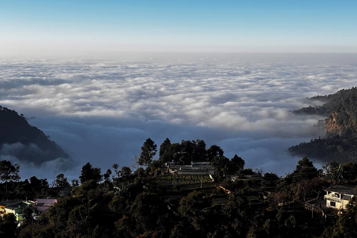 Un paysage montagneux avec un village niché au milieu des arbres, entouré de nuages.