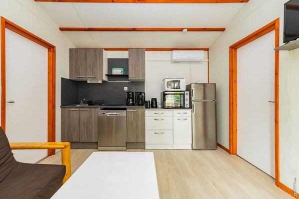 A compact kitchen with wooden cabinets, a microwave, a coffee maker, and a refrigerator.