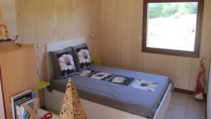 A wooden-paneled room with a bed, a window, and a bookshelf. - Furnished Cottage in the Land of Castles – Ideal for Cycling (Mont-près-Chambord)