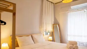 Una camera d'albergo con un letto, uno specchio, una finestra con tende e una lampada.