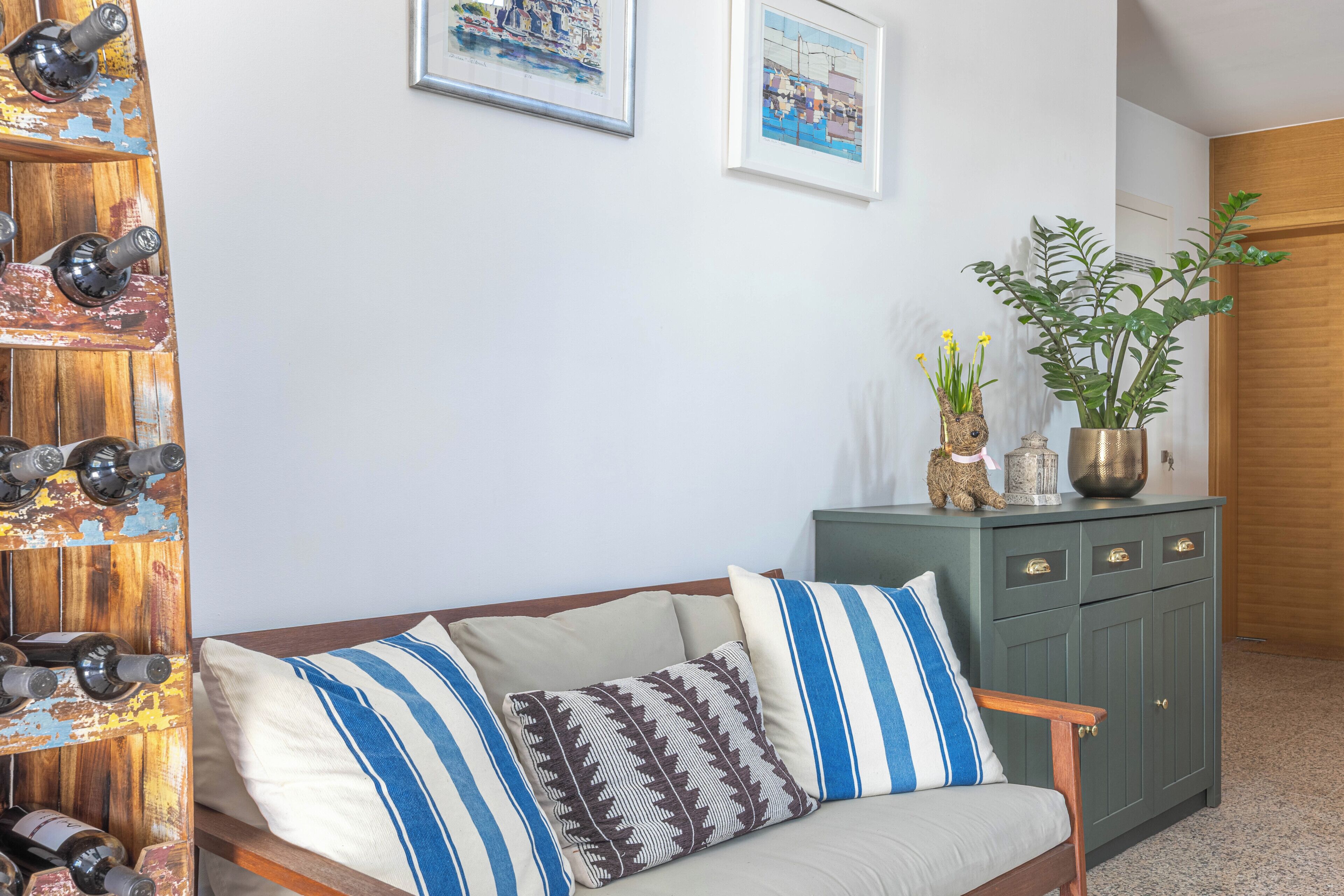 A living room with a sofa, a cabinet with decorative items, and two framed pictures on the wall.