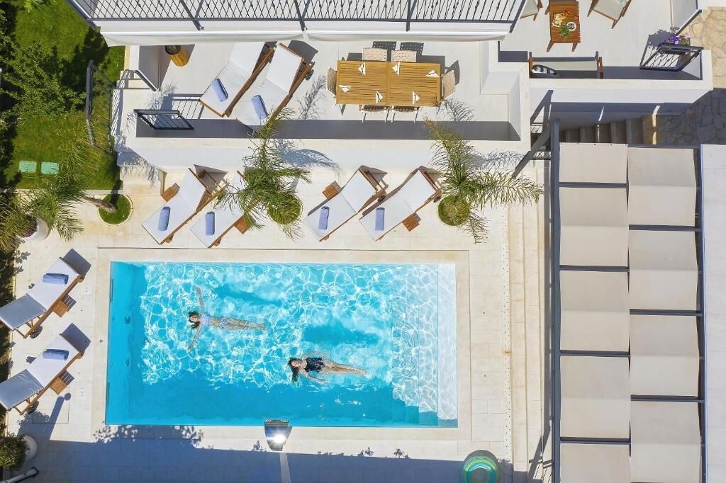Piscina no terraço com cadeiras de espreguiçadeira e área para banhos de sol.