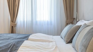 Un dormitorio con cama, cortinas y lámpara de noche.