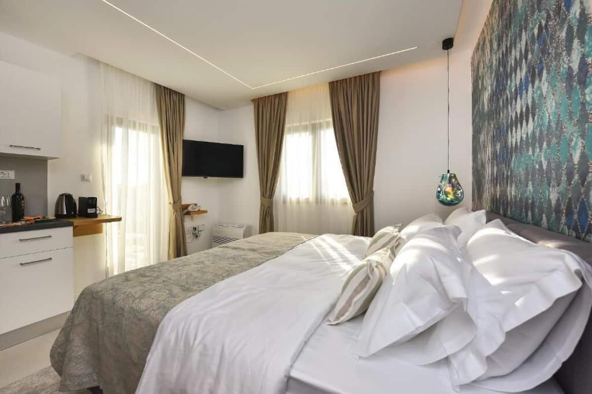 Ein Hotelzimmer mit Bett, Flachbildfernseher, einem Gemälde und einem Fenster mit Vorhängen.