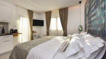 A hotel room with a bed, a flat-screen TV, a painting, and a window with curtains.