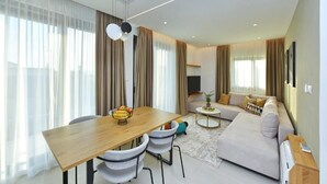 Una sala de estar moderna con una mesa de comedor, sofá y televisor.