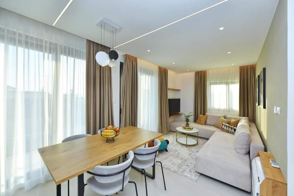Ein modernes Wohnzimmer mit Esstisch, Sofa und Fernseher.