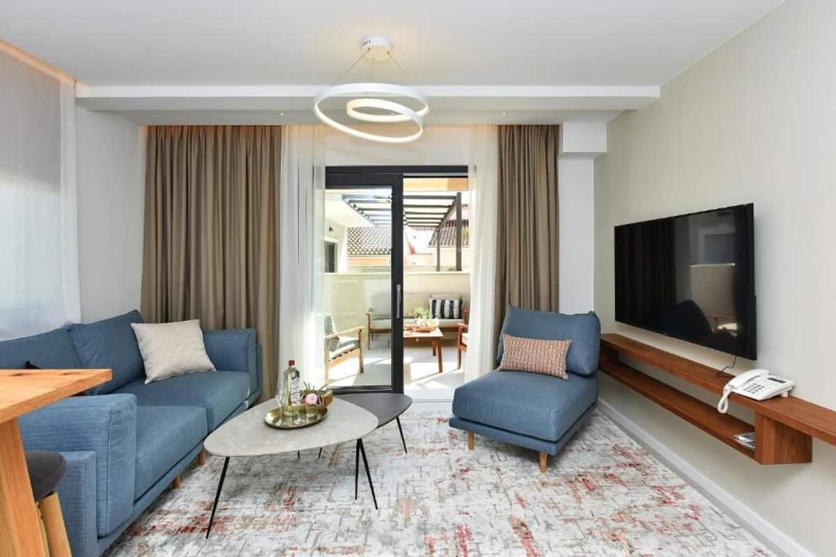 Ein modernes Hotelzimmer mit zwei Sofas, einem Couchtisch, einem Flachbildfernseher und einem Telefon.