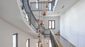 Un interior moderno con una escalera curva, barandillas metálicas y lámparas esféricas colgantes.
