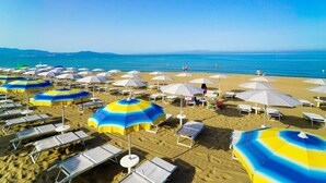A beach with rows of sun loungers and umbrellas, a clear blue sky, and the ocean in the background. - FRUIT VILLAGE PAESTUM Coral Beach (Capaccio-Paestum)