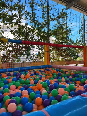 Ein Ballbecken mit bunten Bällen und einem Netz rundherum.