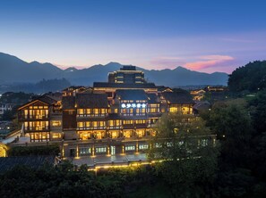 A traditional multi-story building with illuminated windows and a sign in the center. - Chongqing Menghua Lushe Hotel (Chongqing)
